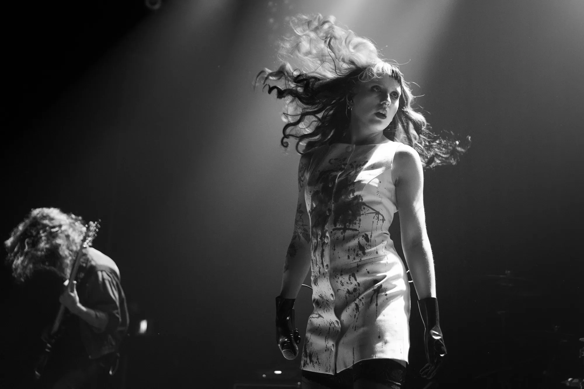 A black-and-white photo of FKA Rayne as she whips her hair, showing off her bloody outfit.