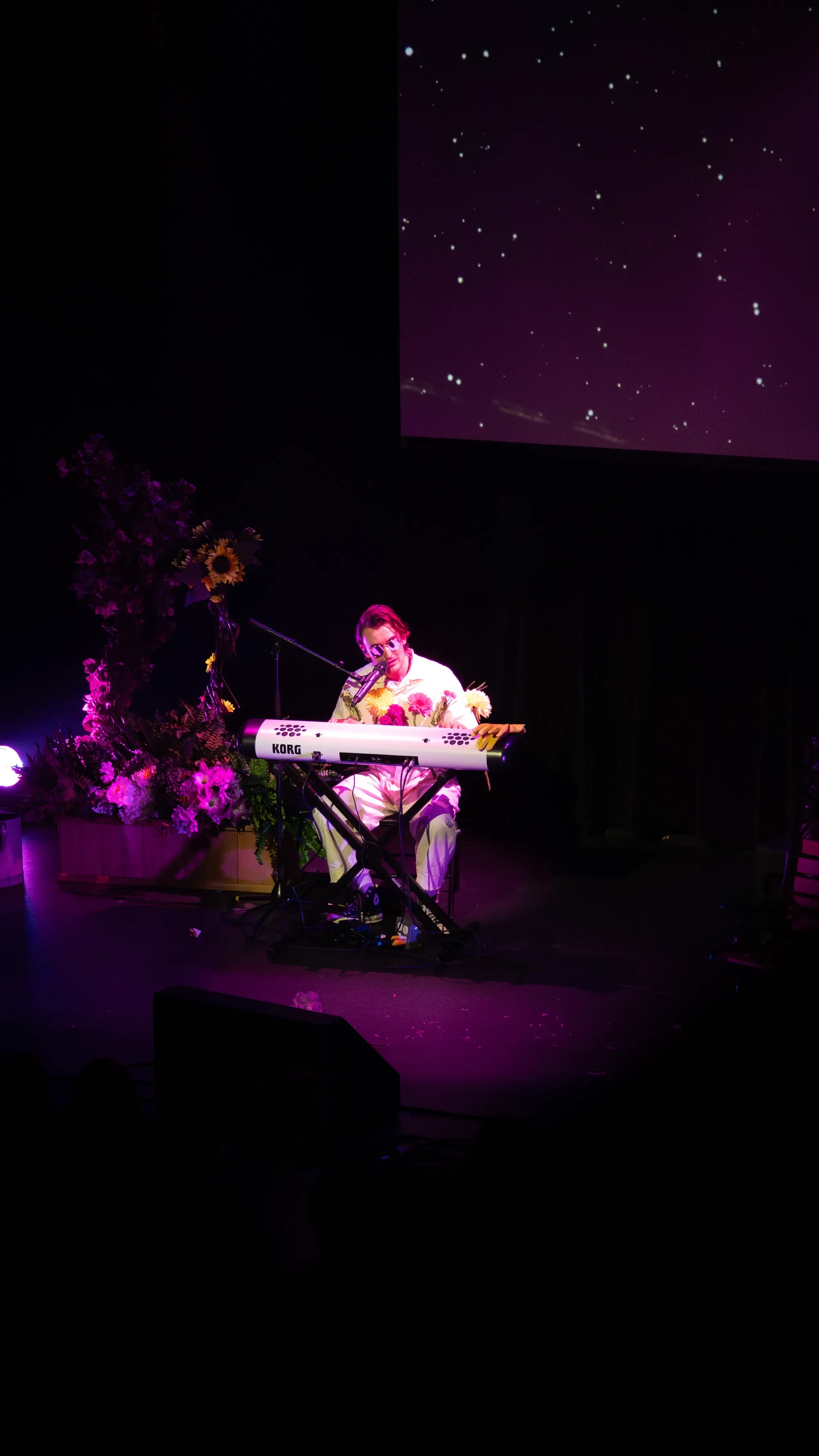 gnash plays keyboard on a flower-decorated stage under purple lighting at The Pearl.