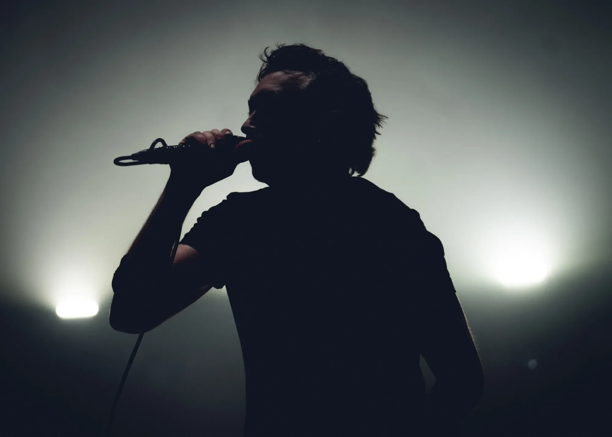 Tim McIlrath of Rise Against silhouetted against Ricochet orange stage wash at PNE Forum