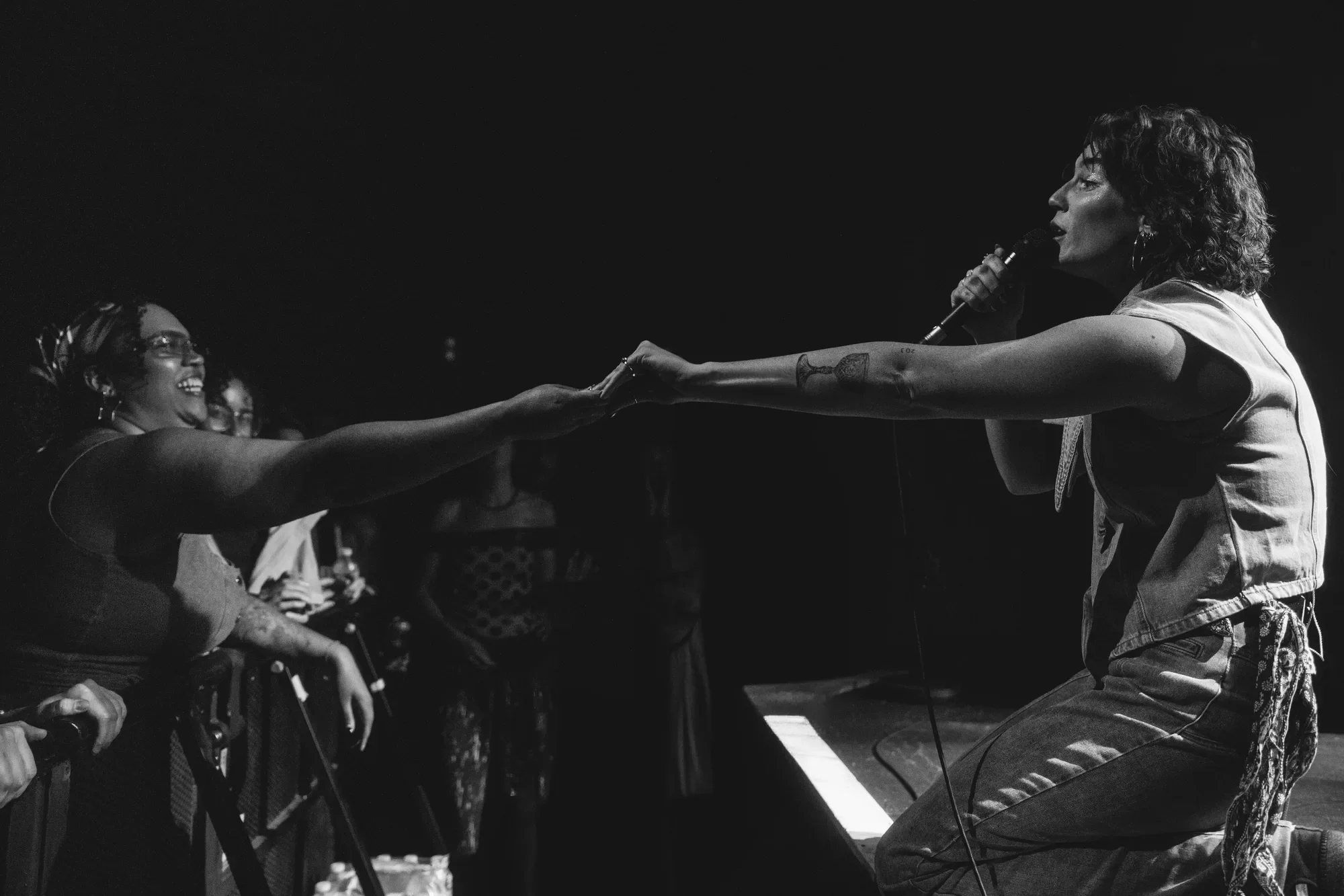 Sammy Rae reaching out to hold a fan’s hand at the edge of the stage.